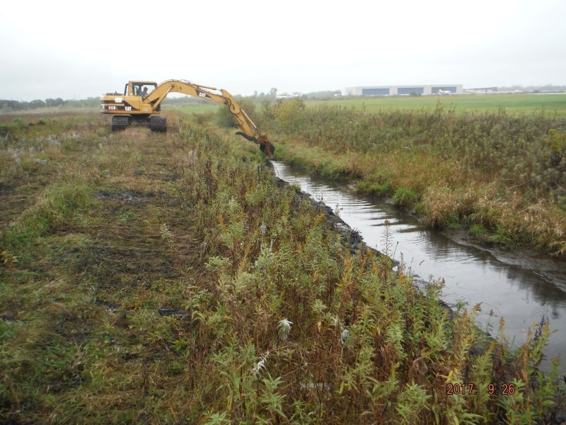 backhoe removing ditch vegetation