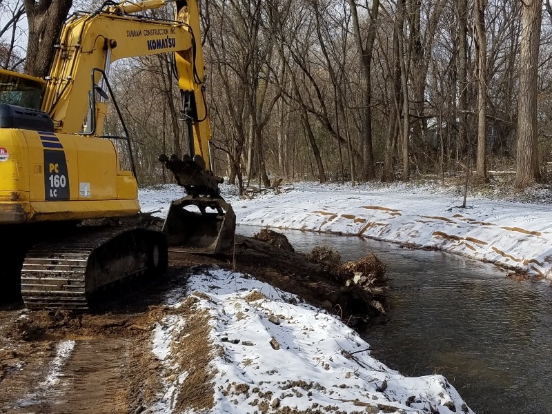 Backhoe installing tree rootwads into bank for increased habitat in the channel