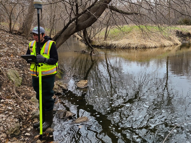 Man inspecting ditch with survey equipment.jpg