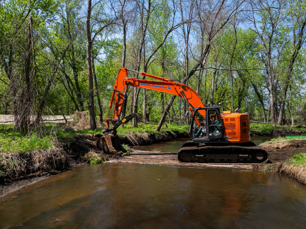 Photo of excavator crossing a portion of Lower Coon Creek during active restoration