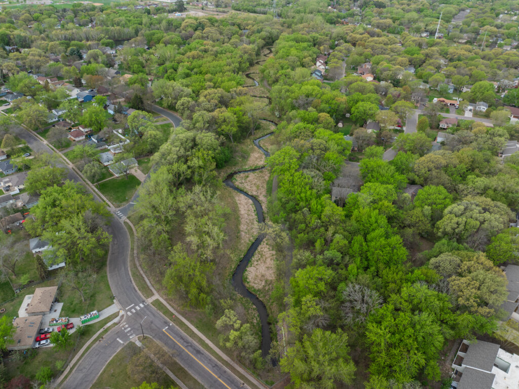 Oblique aerial photo of Sand Creek post-restoration. Image highlights the suburban neighborhood surrounding the Creek.
